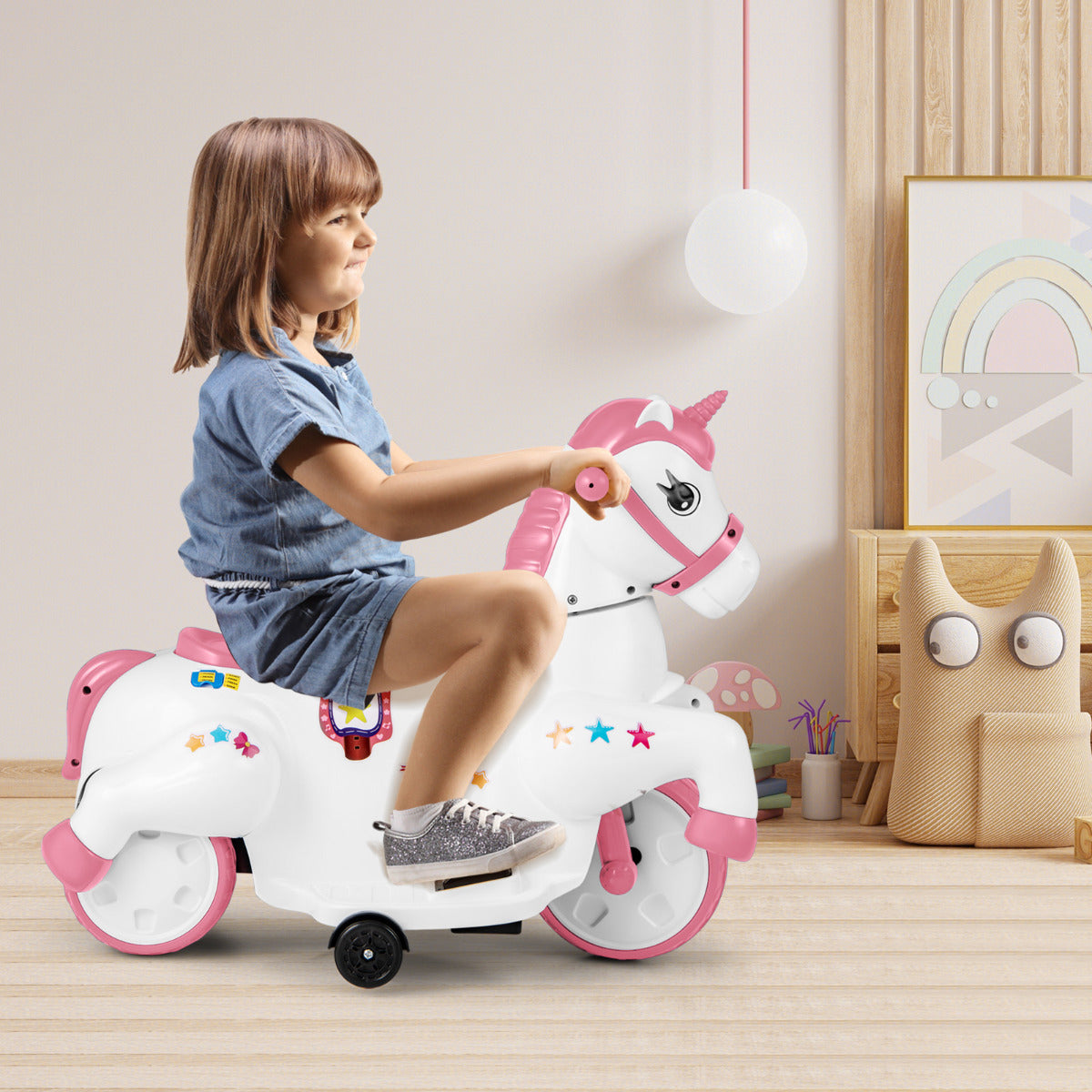 A girl in a denim dress rides the pink unicorn electric toy in a room