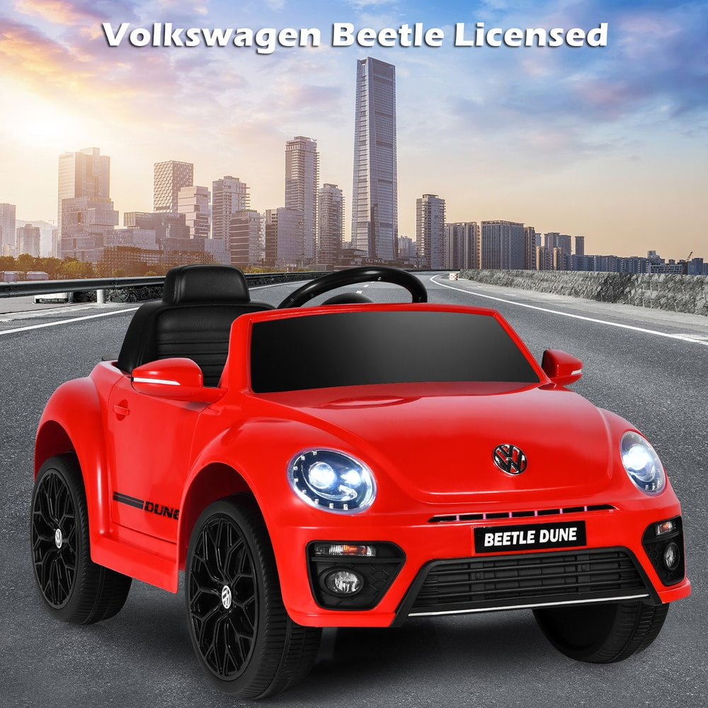 Red kids electric ride on car with a city skyline in the background