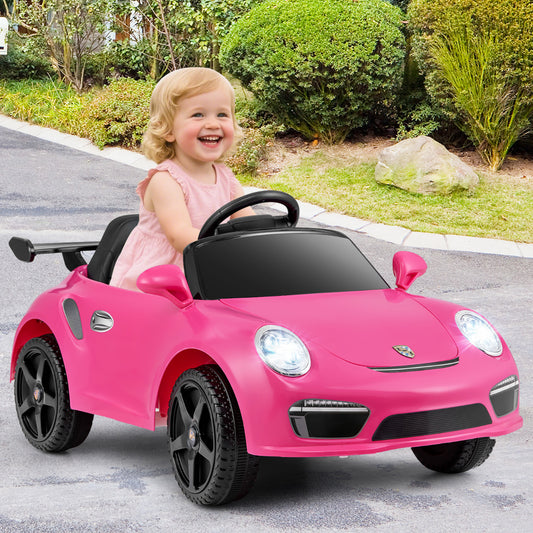 A happy toddler drives the rose pink electric car on a paved path outdoors