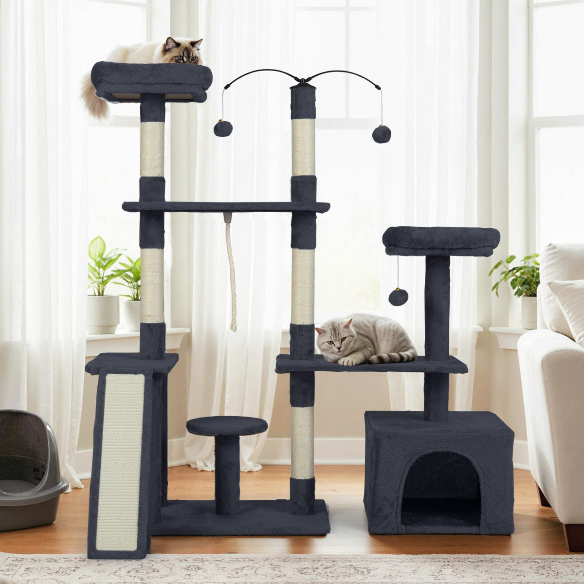 The cat tree standing in a bright room next to a window with a cat on the top perch