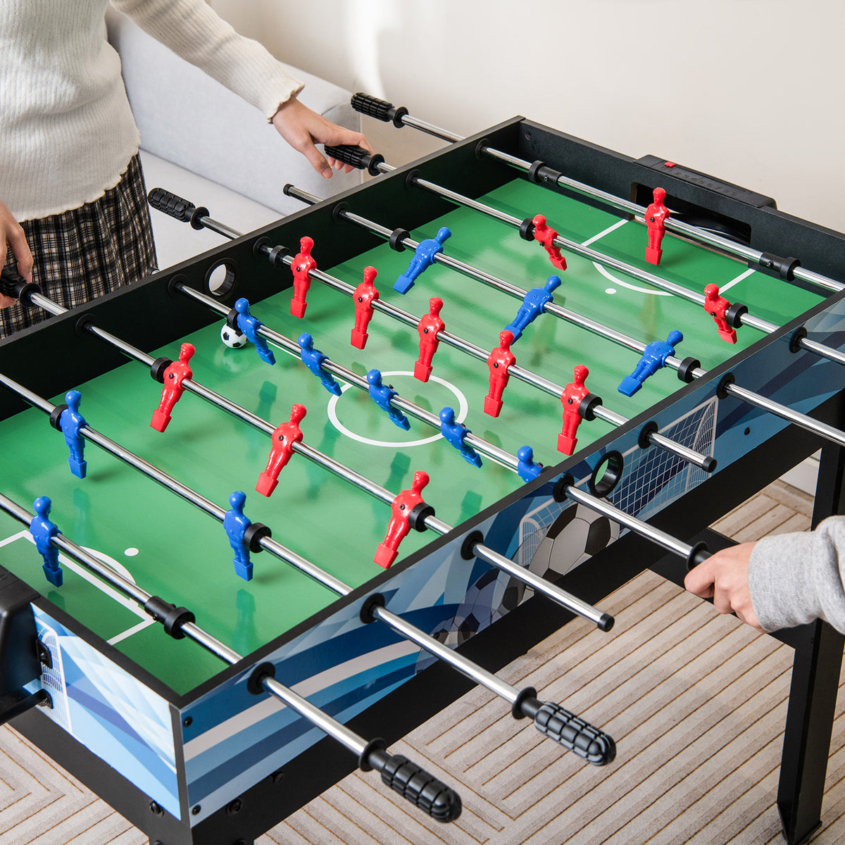 The game table being used for a competitive match of foosball by two people