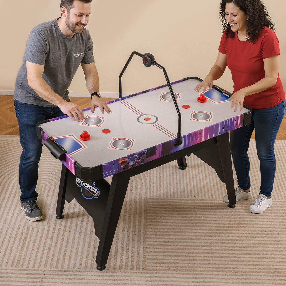 Adults playing air hockey on a white and purple table in a living room