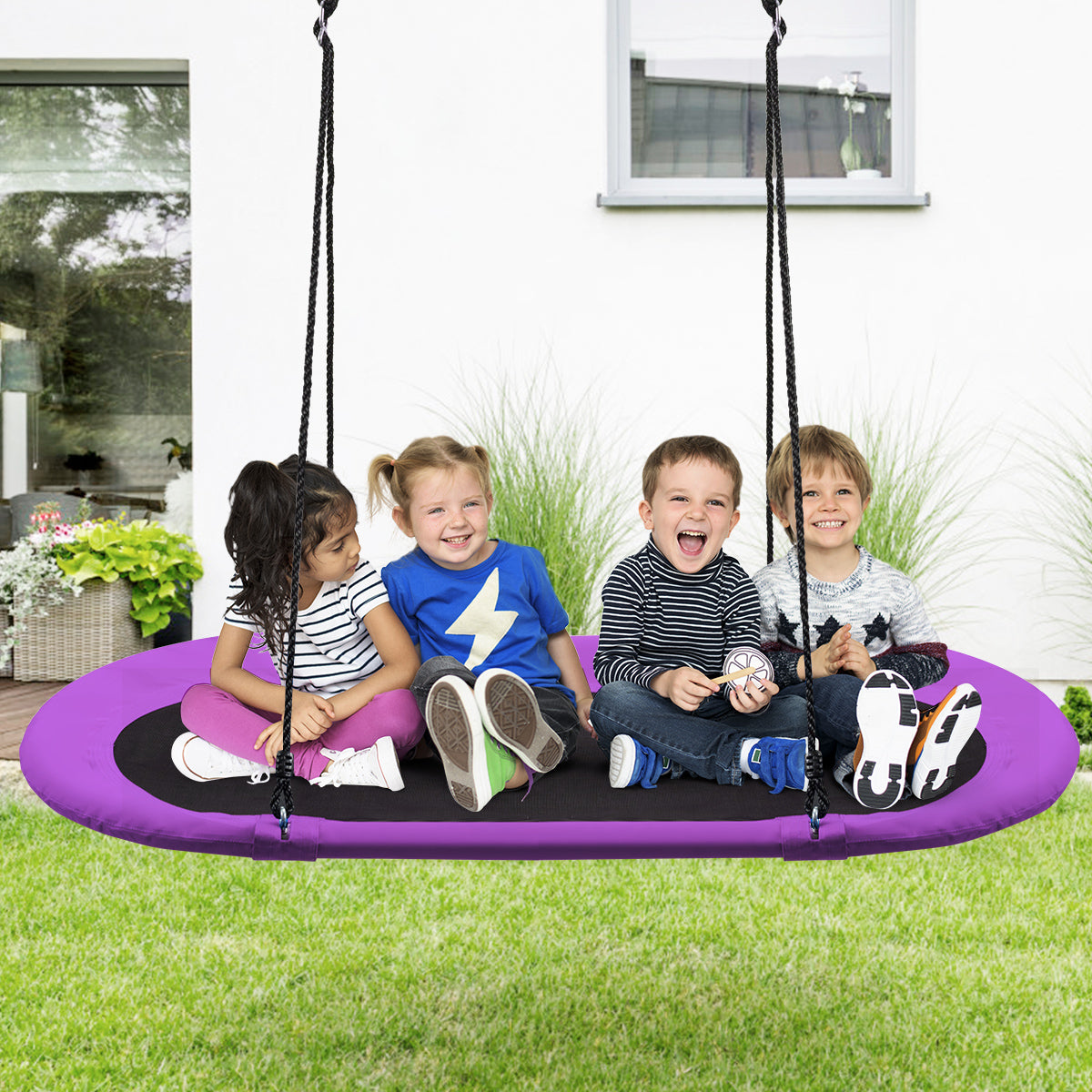 Four children sit on the oval swing in a garden setting
