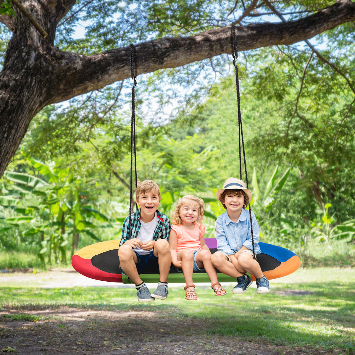 Three children sitting on the oval swing suspended from a tree branch in a garden
