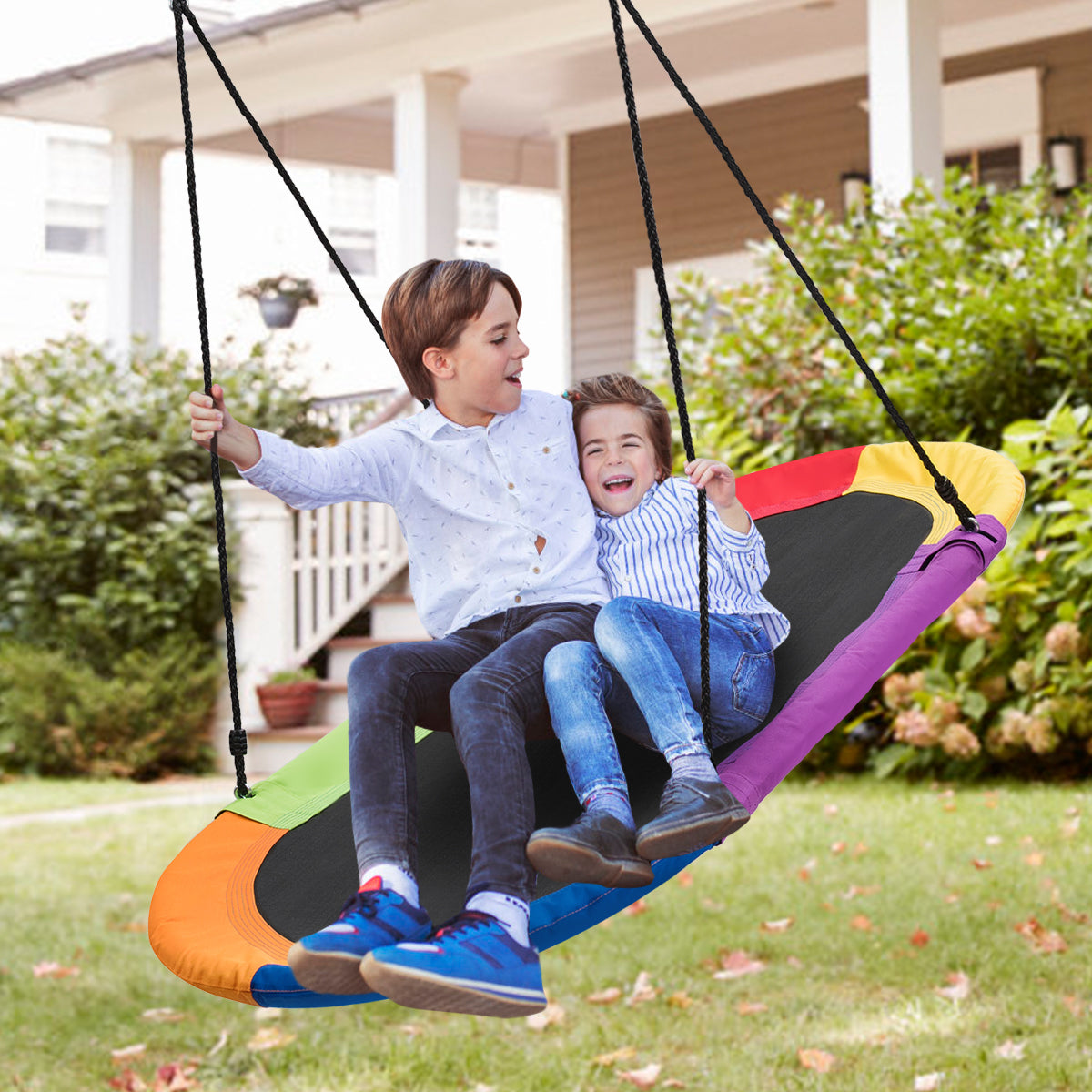 Two boys enjoying the multicoloured oval swing in a garden setting