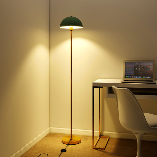 The standing lamp lit up in the corner of a room next to a desk and chair