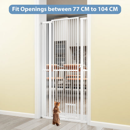 A small cat stands in front of the tall white metal pet gate, which is installed in a doorway