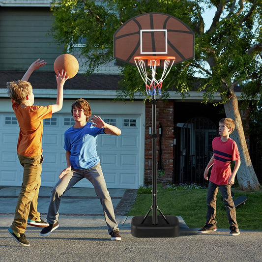 The basketball hoop being used by three boys playing on a driveway