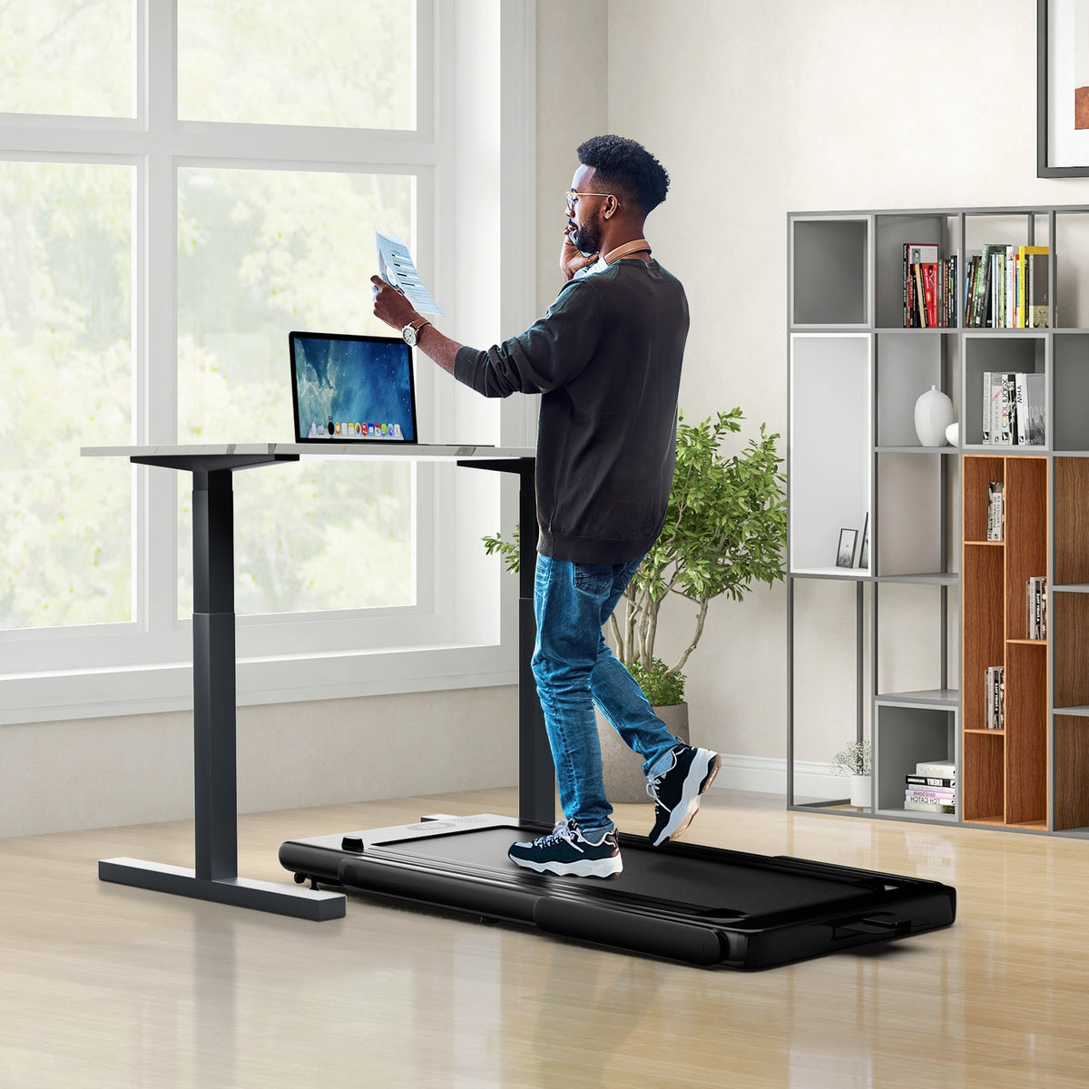 the walking pad placed under a standing desk with a person walking while working