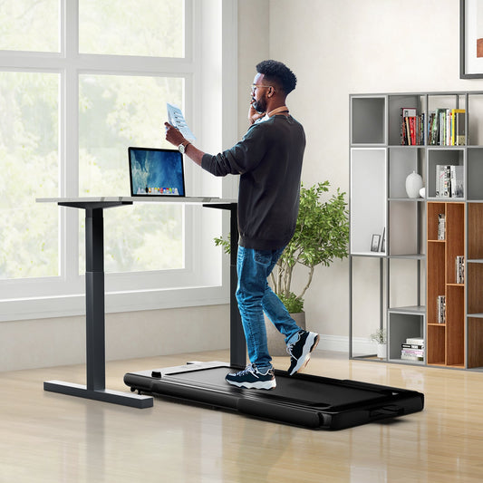 the walking pad placed under a standing desk with a person walking while working