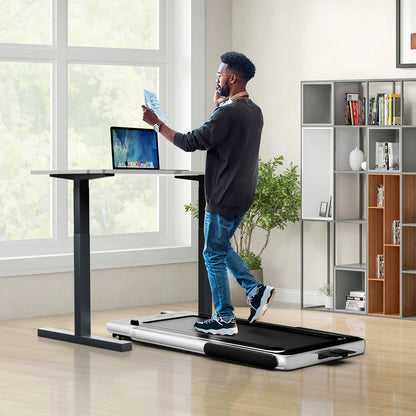 The walking pad treadmill being used under a standing desk with a man working