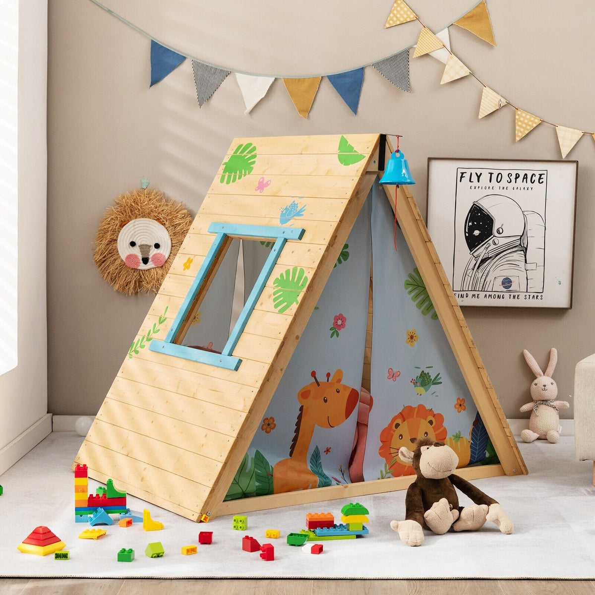 The children's climbing playhouse set up indoors with toys around it and bunting above