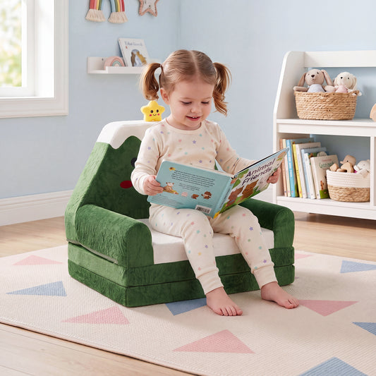 A young girl sits reading a book on the green kids sofa to lounger in a nursery room