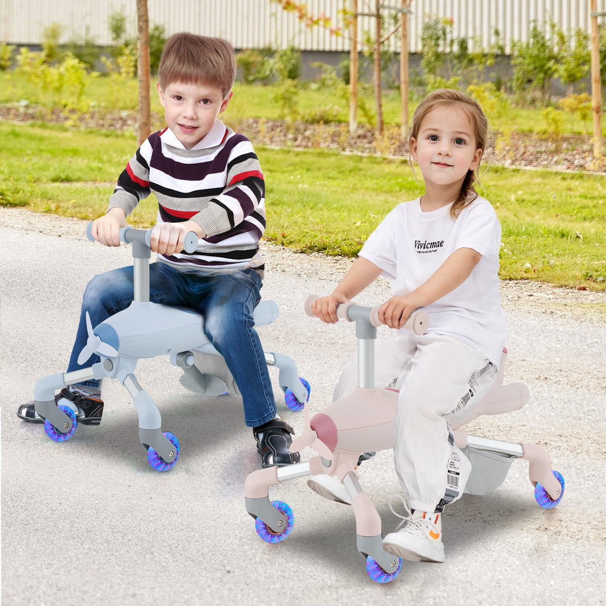 Two children sitting on the ride on toy in different colours on a paved path in a garden