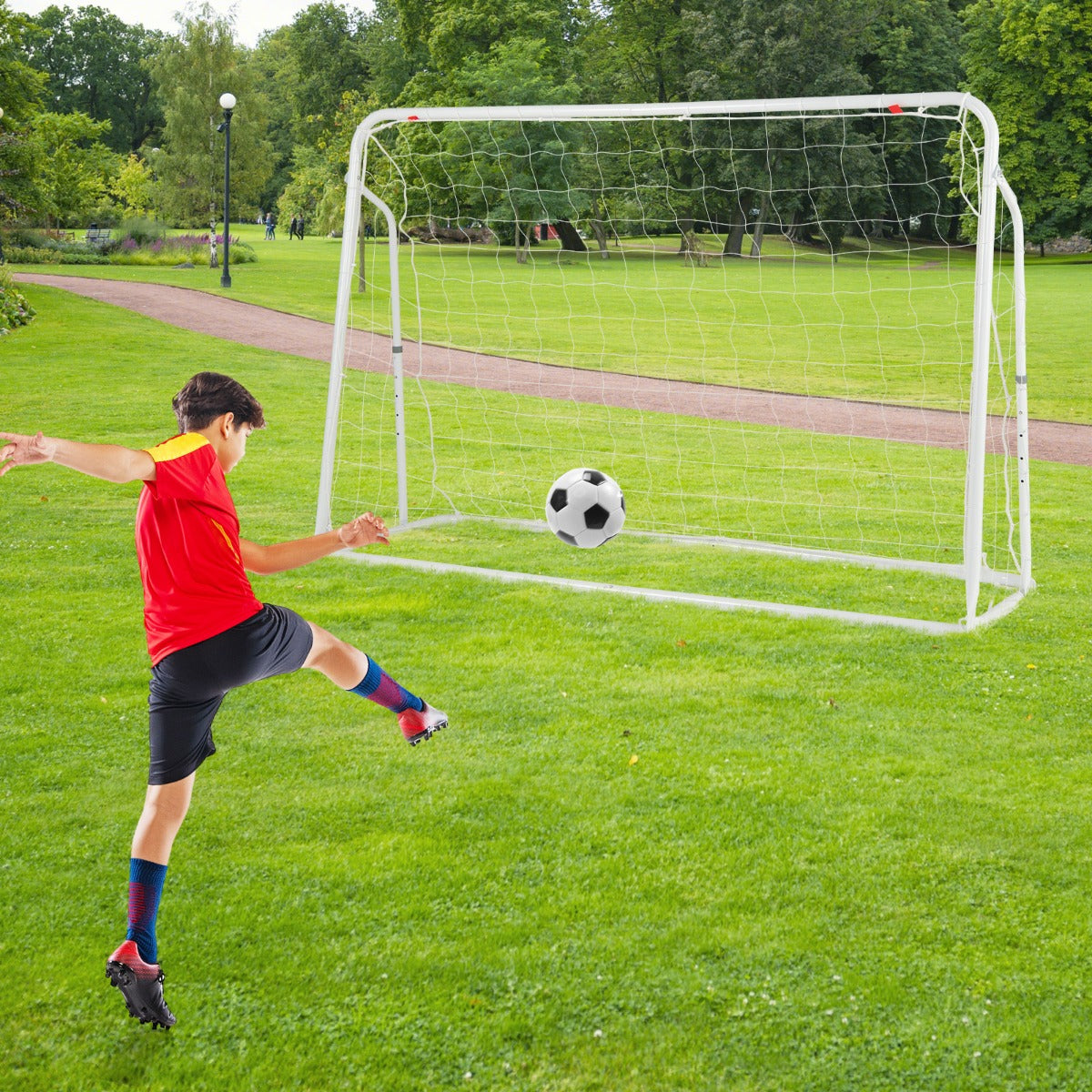 Kids soccer rebounder set up as a goal in a park with a boy kicking a ball towards it