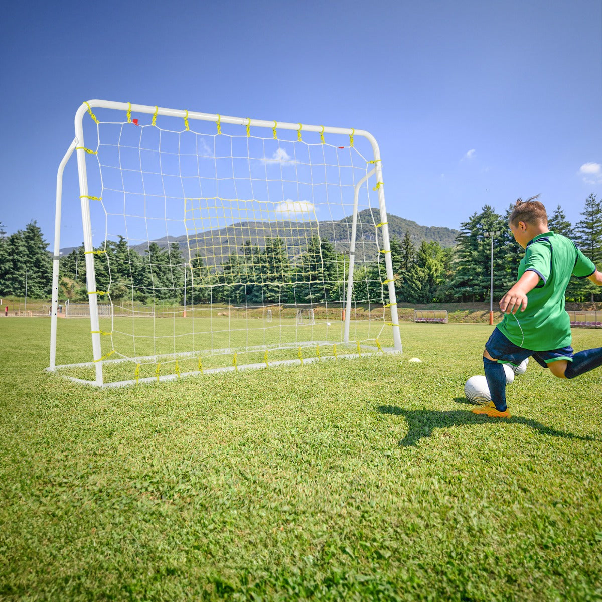 Children playing football with the soccer goal in a grassy field with mountains behind