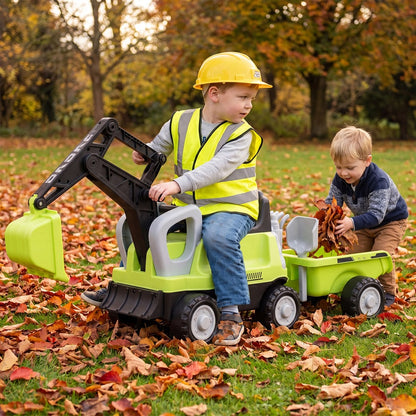 Two boys play with the ride on push car and trailer in autumn leaves