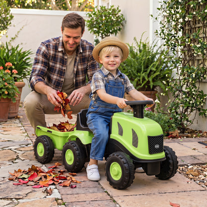 A father and child play with the green ride on tractor with trailer outdoors