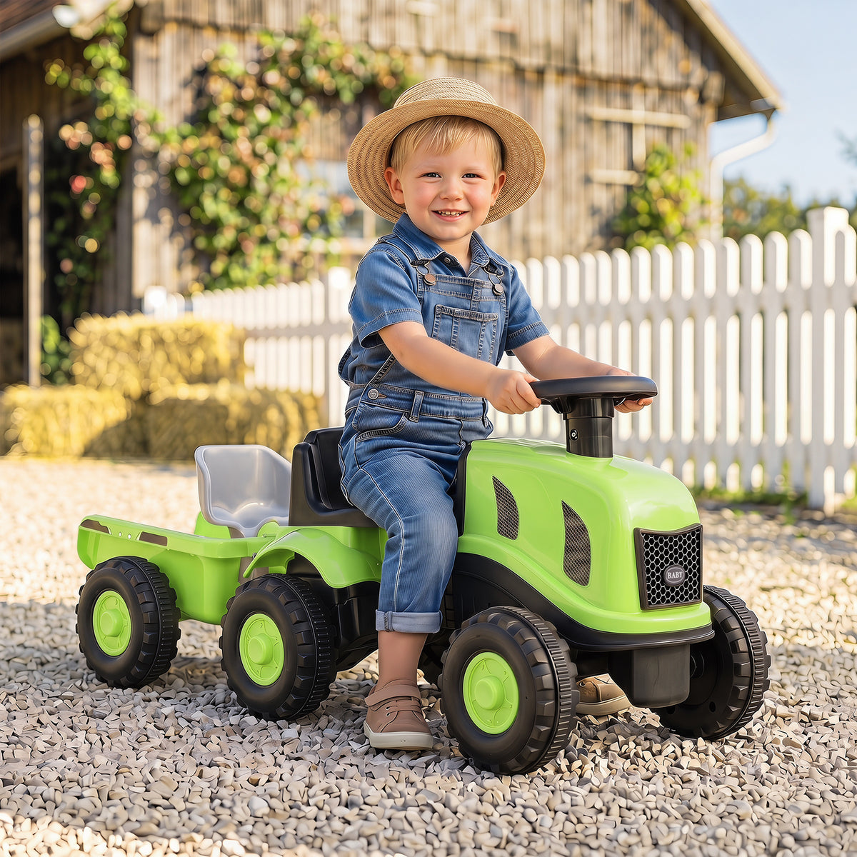 The green ride on tractor with trailer is shown outdoors on a gravel path