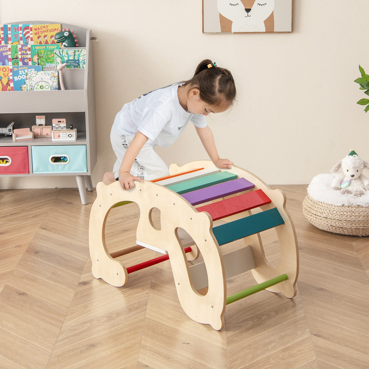 A young child climbs over the natural wood rocking horse arch with rainbow steps