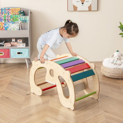 A young child climbs over the natural wood rocking horse arch with rainbow steps