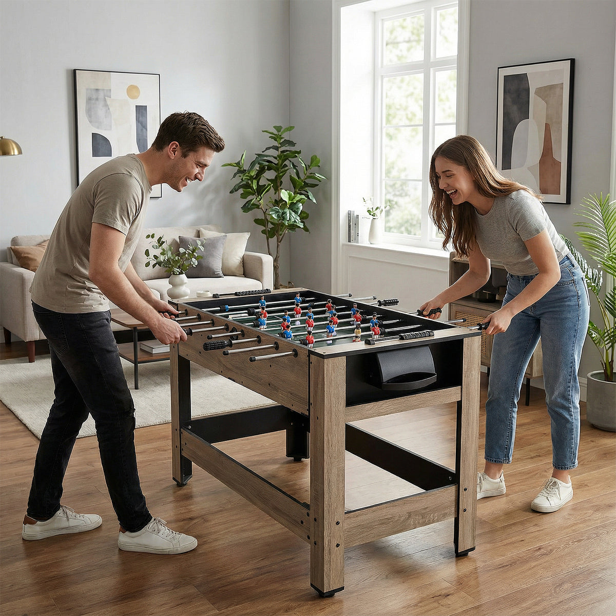 A man and woman playing foosball on the wooden game table in a bright living room setting