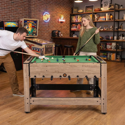 The game table set up for pool with a woman holding a cue stick in a home bar environment