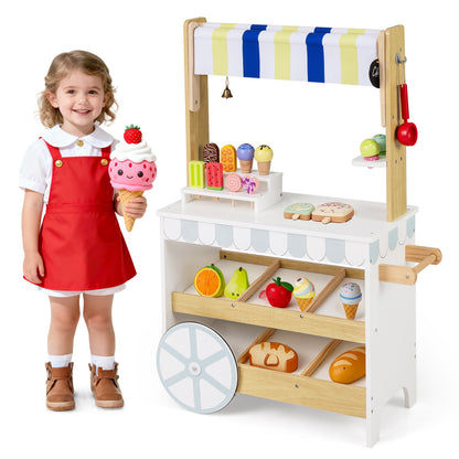 A child holds a large ice cream toy next to the wooden ice cream cart