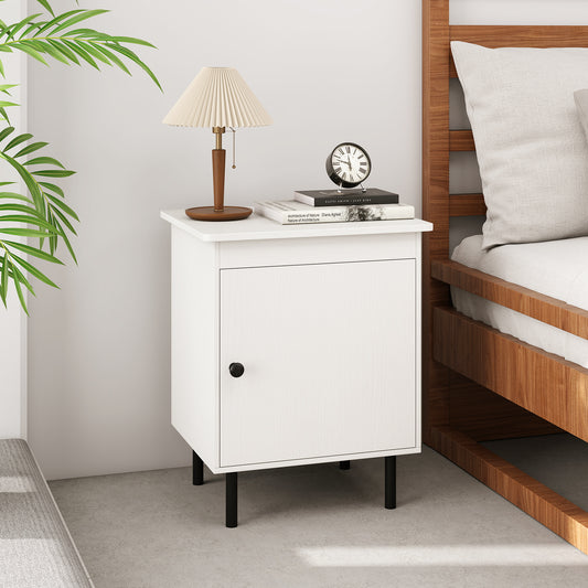 The white nightstand with a single door cabinet is shown in a bedroom with a lamp and books on top