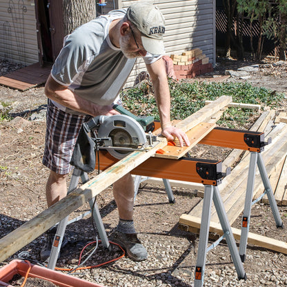 Man using a circular saw on wood supported by saw horses