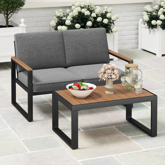 The patio furniture set placed on a paved patio with a bowl of fruit and a glass pitcher on the table