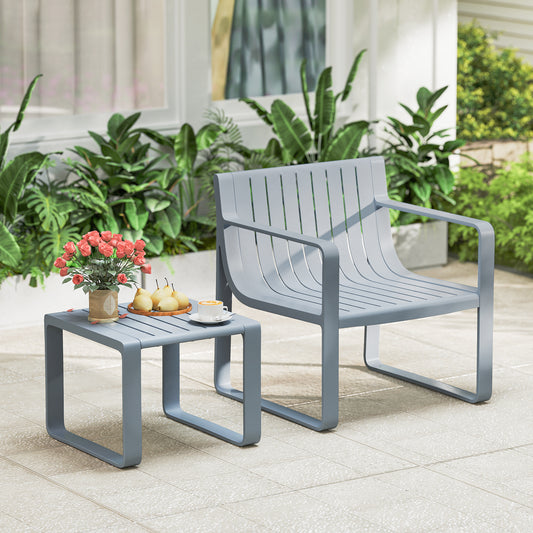 Grey patio furniture set with a chair and coffee table on a paved patio with plants