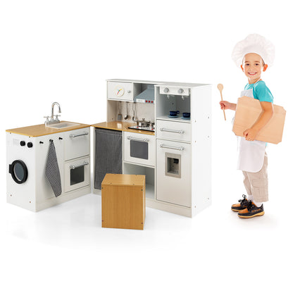 A boy in a chef hat stands next to the play kitchen set holding a wooden board