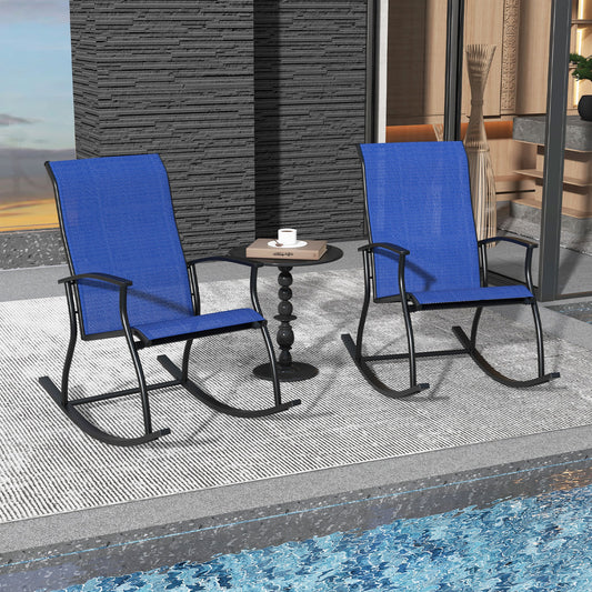 Two navy blue outdoor rocking chairs with a small black table on a patio by a swimming pool