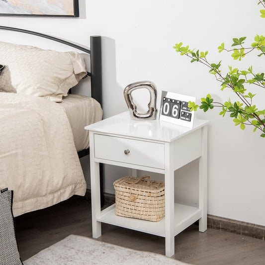The white bedside table positioned beside a bed with a small woven basket on the bottom shelf
