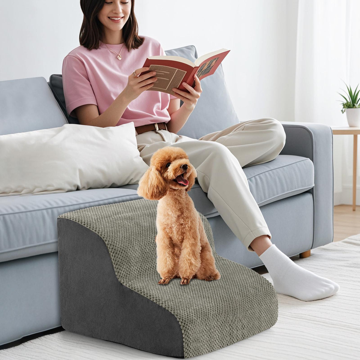 The pet stairs positioned next to a sofa where a person is reading a book with a dog