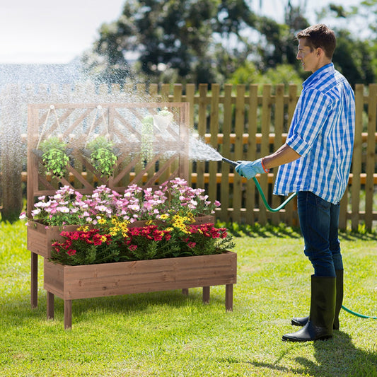 Man watering a raised garden bed with trellis in a garden setting