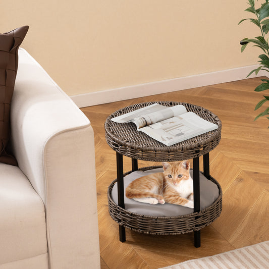 The wicker kitten house with a cat on the lower tier, placed next to a sofa indoors
