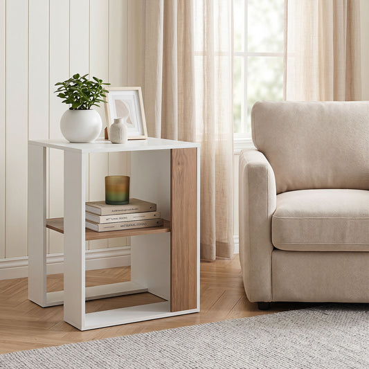 The end table in a living room next to a sofa, styled with a plant and books