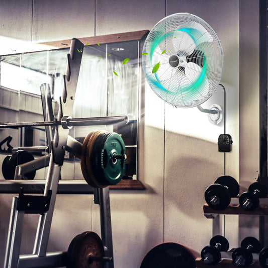 The wall fan mounted in a home gym with weights and equipment visible in the background
