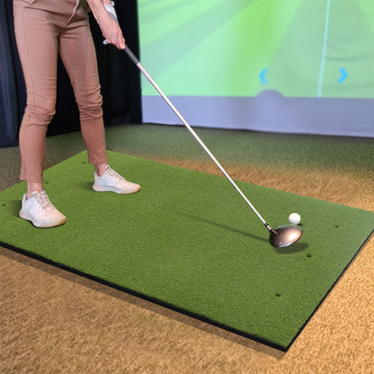 Woman hitting a golf ball on a golf hitting mat indoors