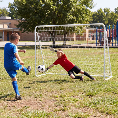 Children playing soccer in a field with one boy as goalkeeper