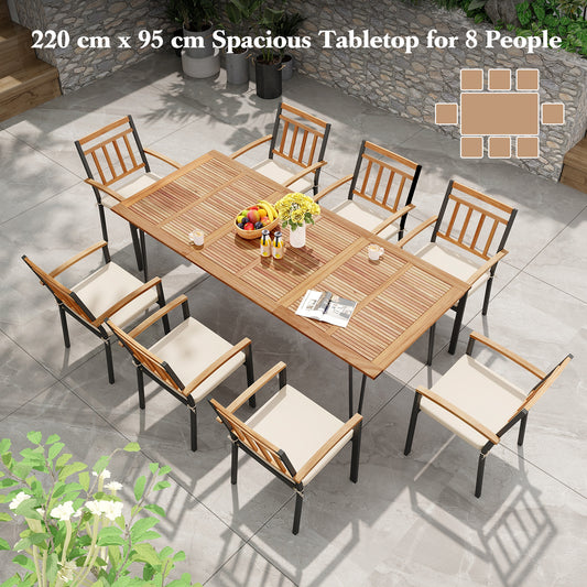 The patio table surrounded by eight chairs with cushions on a stone patio in a garden