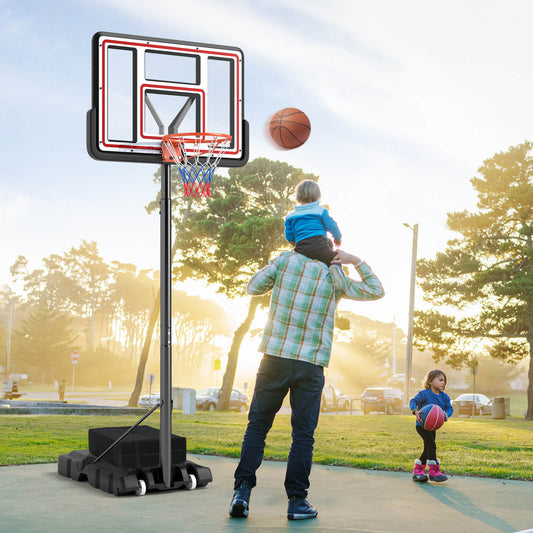 A father and two children playing with the portable basketball hoop in a park
