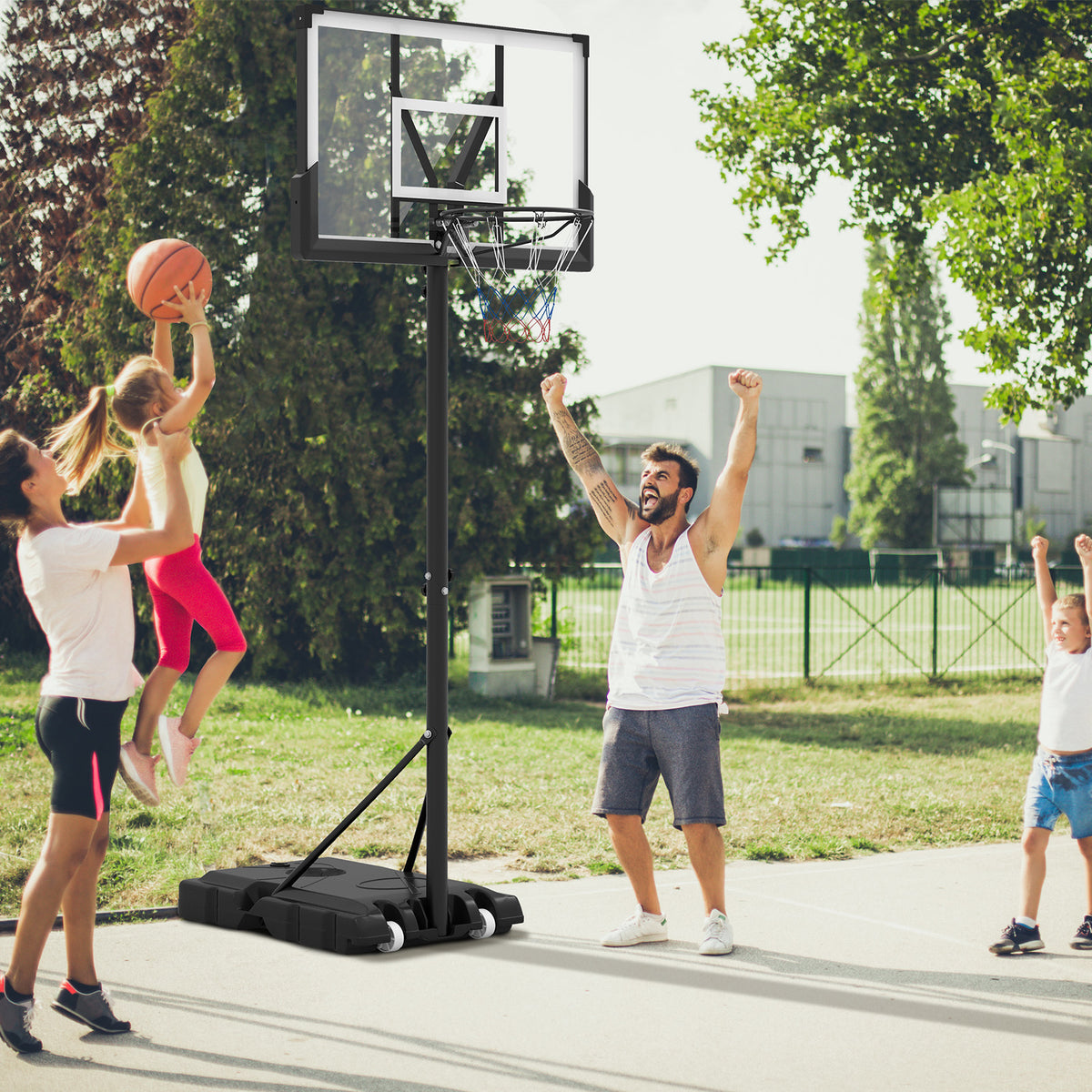 A family playing basketball on an outdoor court with the adjustable basketball hoop