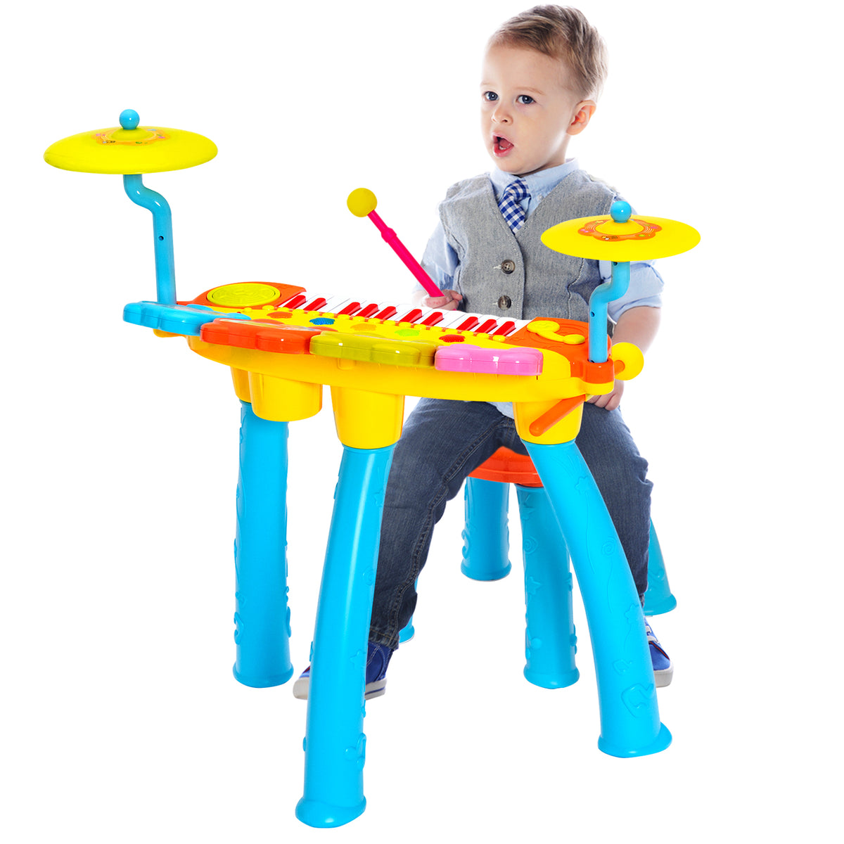 A young boy sits at the blue and yellow toy keyboard drum set, holding a drumstick