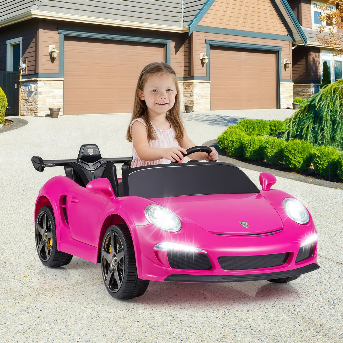 A young girl drives the pink kids electric car on a driveway