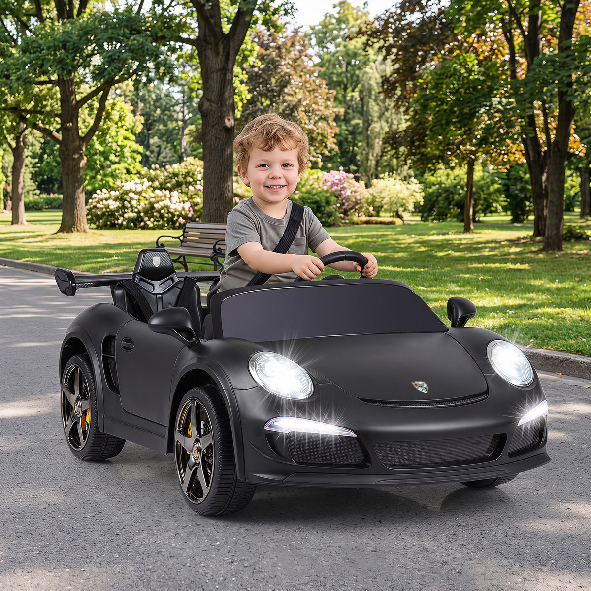 The kids electric car being driven by a young boy on a paved path in a park