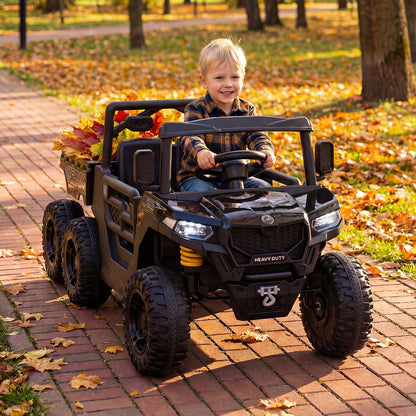 Child driving the black electric dump truck in a park with autumn leaves