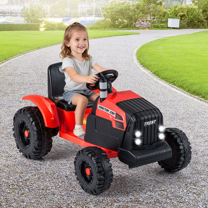 A happy child steers the red ride on tractor with trailer across a paved garden path
